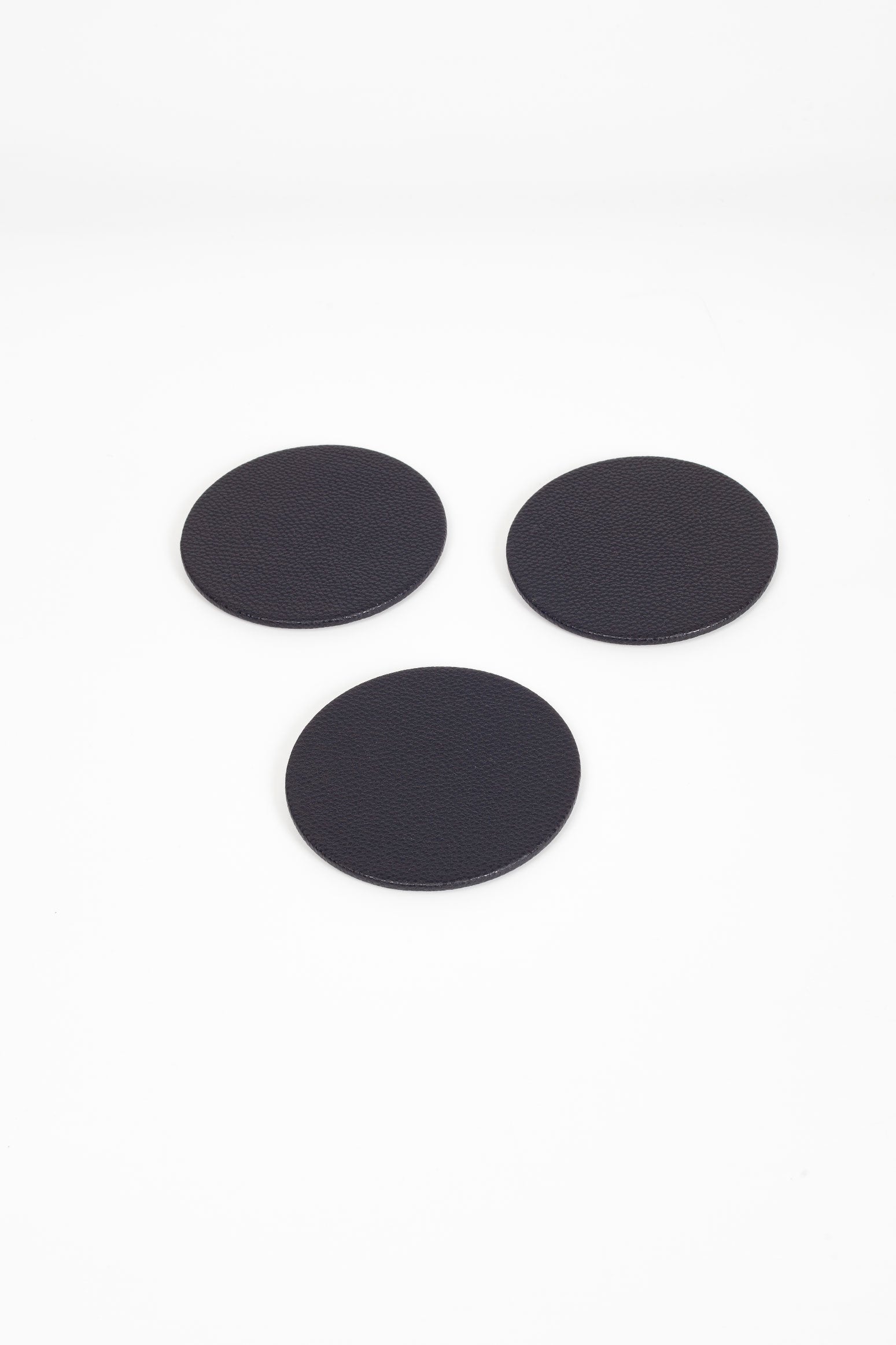 مجموعة من مساند الأكواب المصنوعة من الجلد على شكل بيضاوي باللون الأسود