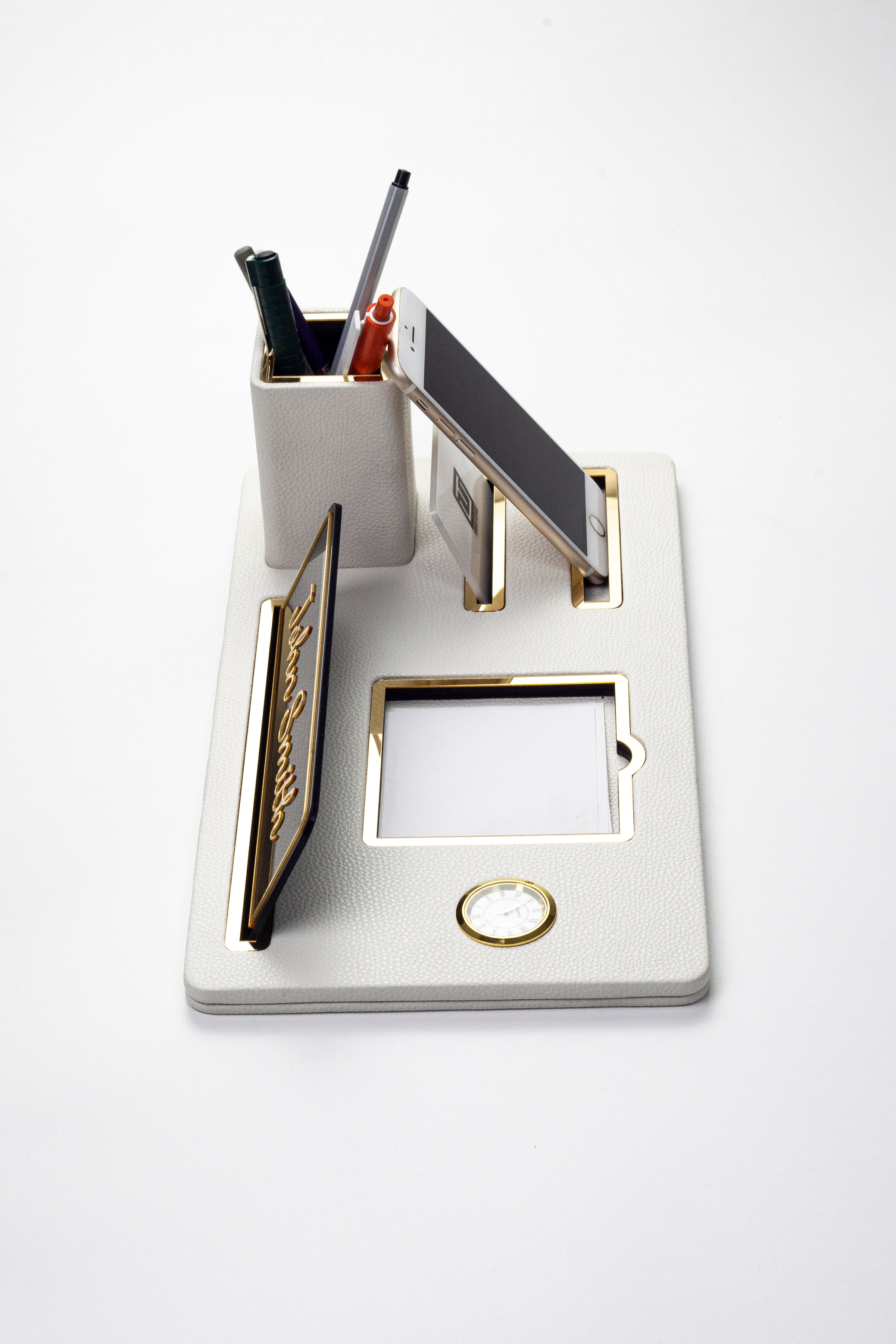 لوحة اسم مكتبية من الجلد، منظم مكتب، ساعة ذهبية بيضاء مزينة بتفاصيل، حامل أقلام.